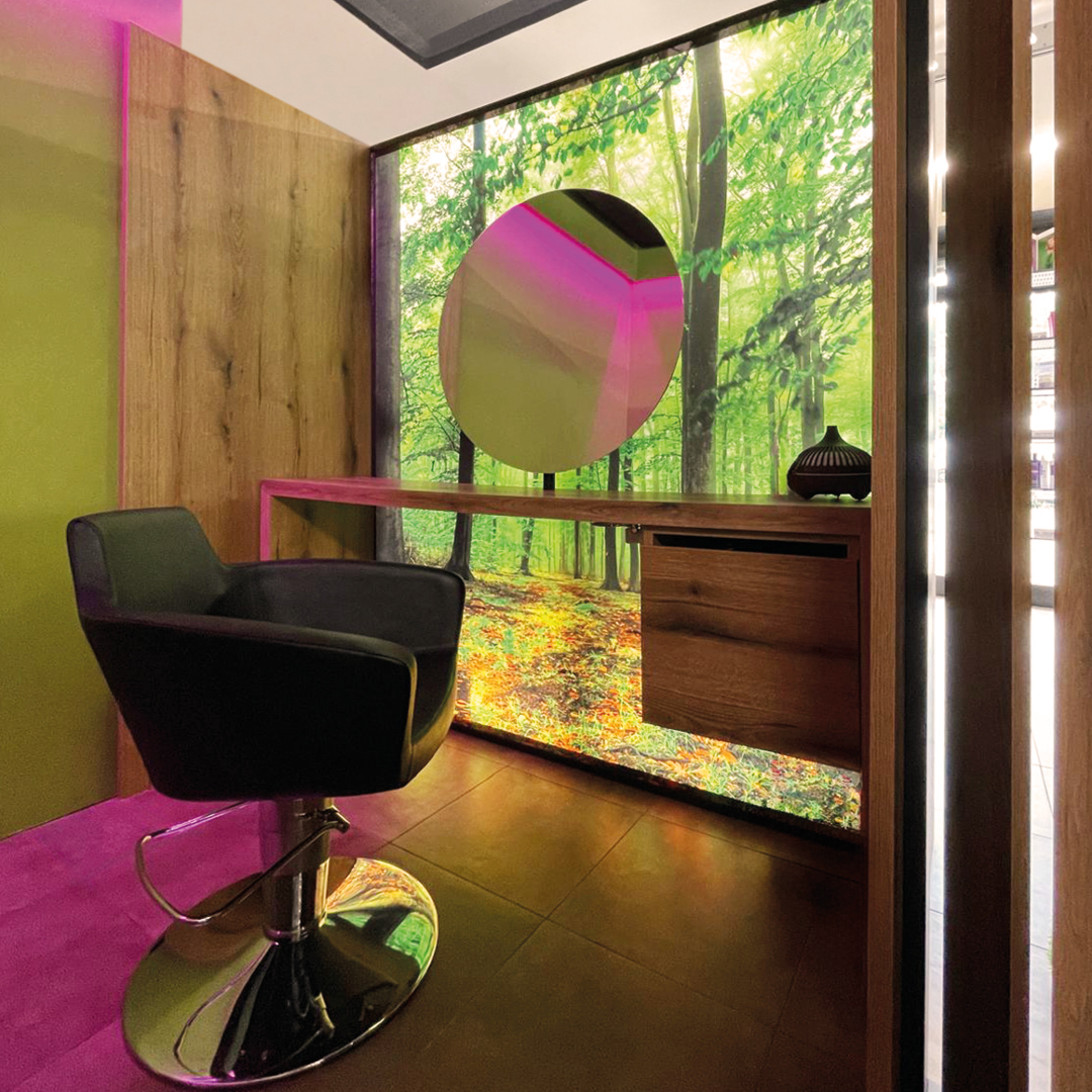 Immagine angolo della tricoroom con poltrona e specchio decorata con elementi naturali e luci led rosa 